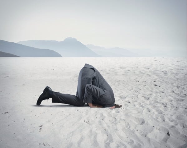 man hiding from covid, with his head buried in the sand