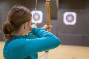 Work-life balance hobbies woman with archery bow and target 